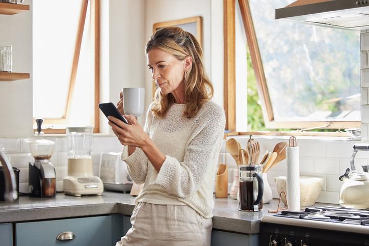 Woman using phone at home in kitchen